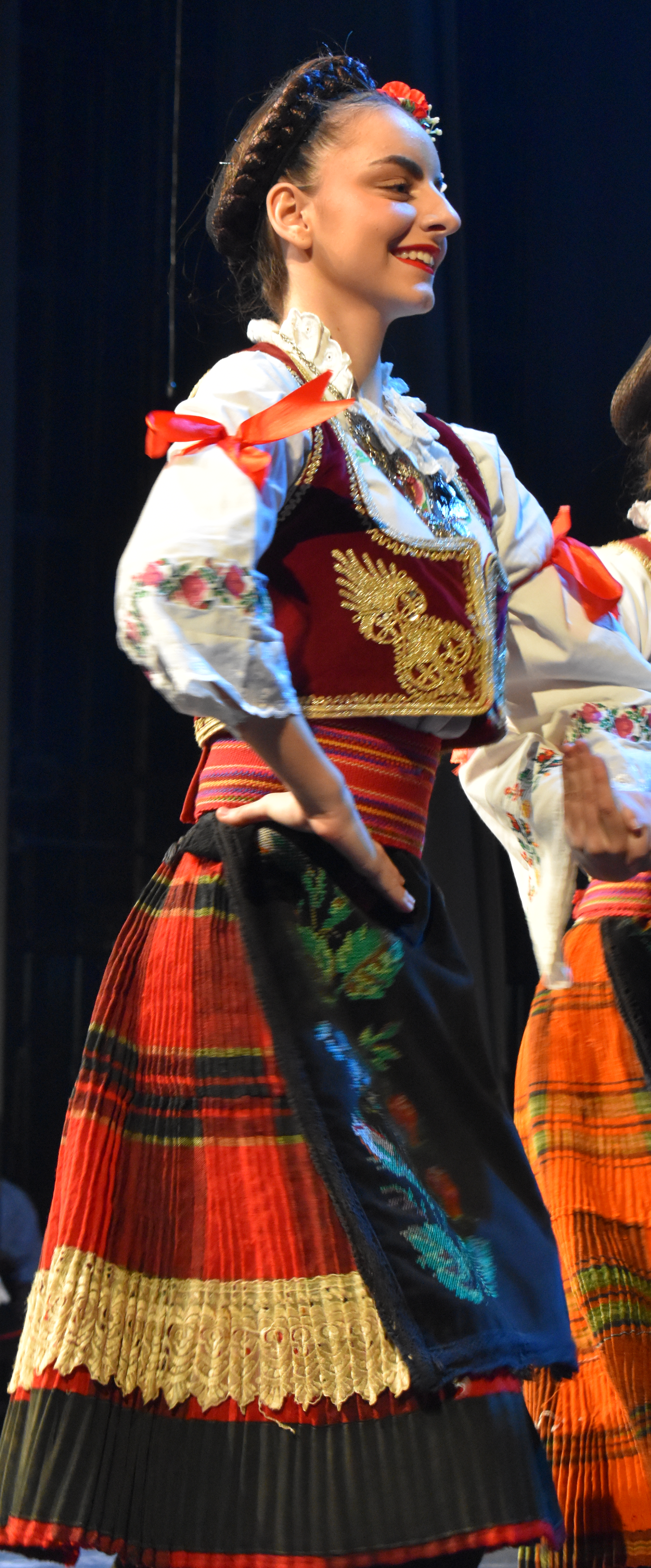 Mlada žena u srpskoj narodnoj nošnji nastupa na sceni / Young woman in traditional Serbian folk costume performing on stage
